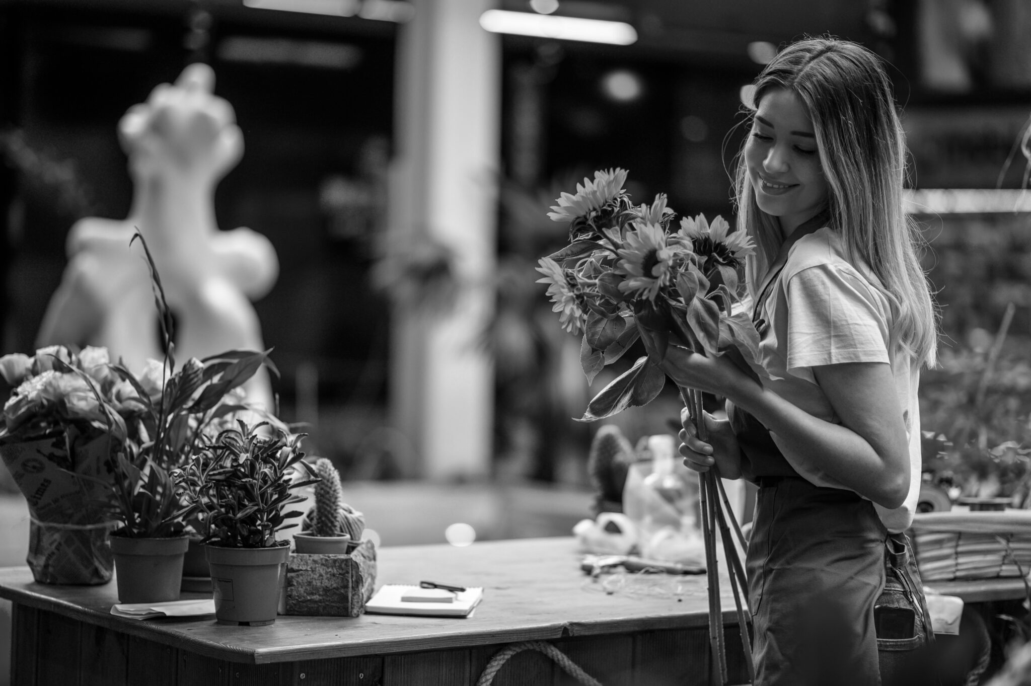 Beautiful woman florist standing and holding bouquet of sunflowers in flower shop