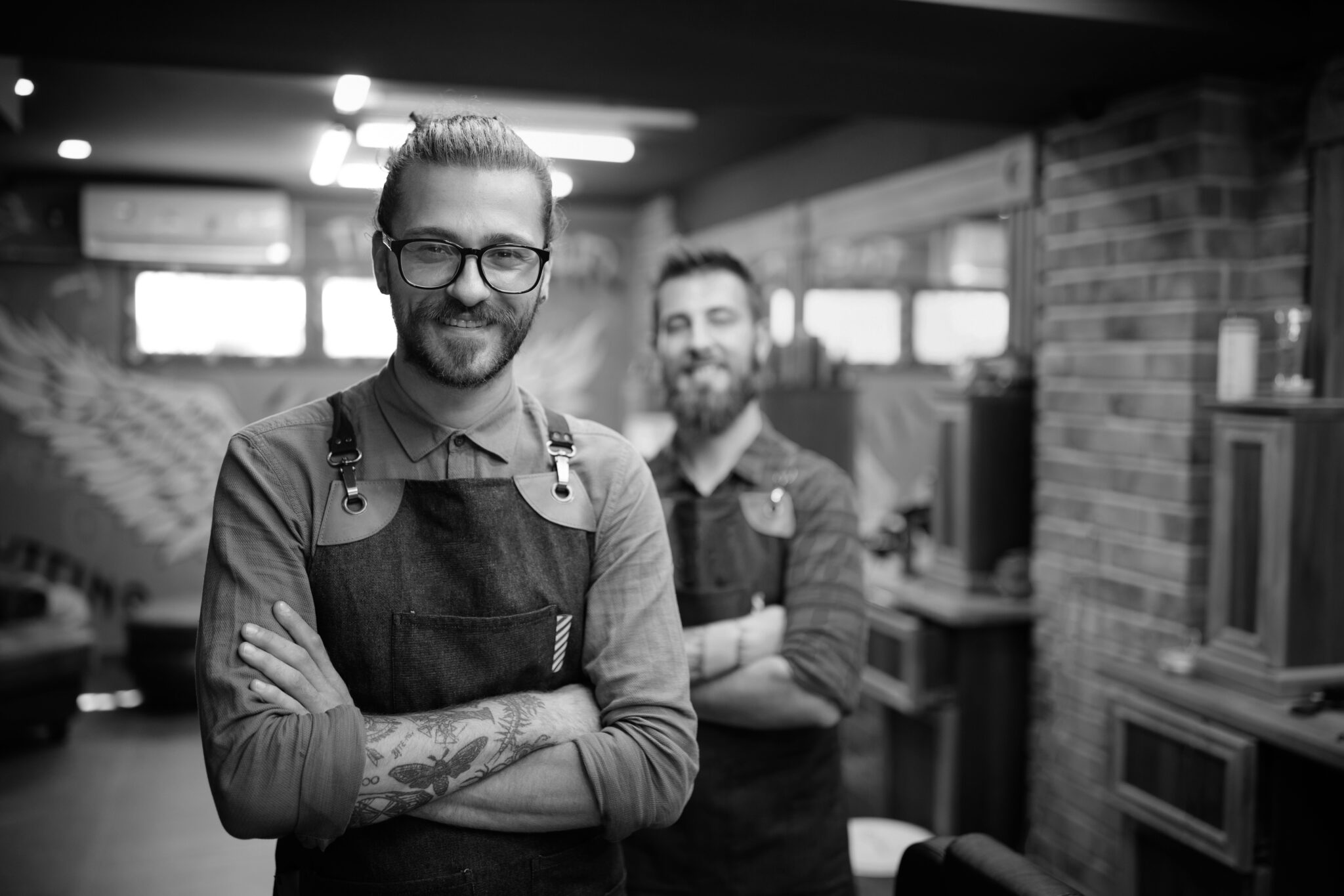 Portrait of tattooed young male barbers and hairdressers in barber shop